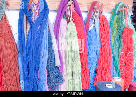 Hand dyed and handspun wool with a range of vibrant colours hanging on pegs in studio Stock Photo