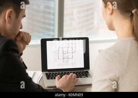 Architects working with building plan on laptop screen, close up Stock Photo