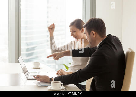 Happy excited team looking at laptop, celebrating great business Stock Photo