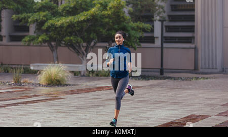 Woman runner in jogging outfit running on a street. Woman