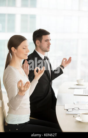 Relaxed mindful businessman and businesswoman meditating at work Stock Photo