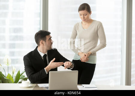 Irritated boss pointing on wristwatch while nervous employee mak Stock Photo