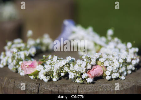 Bridal flower crown of baby's breath with small pale pink roses set on a tree stump, rustic minimalist wedding theme with shallow depth of field Stock Photo