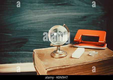 Old blackboard with chalk, books, a globe and a pencil. A beautiful backdrop for education, a free space for your text. Back to school. Shallow DOF. Stock Photo