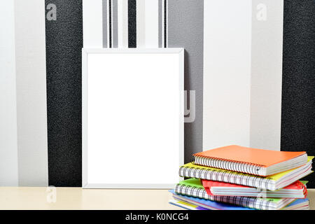 Poster frame mock up template with colored notebooks on wooden table Stock Photo