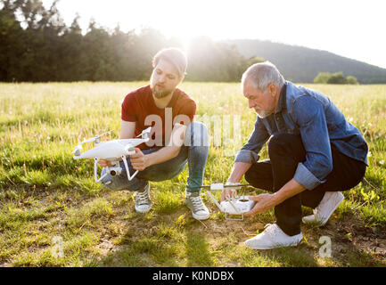 Senior father and his adult son with drone on a meadow Stock Photo - Alamy