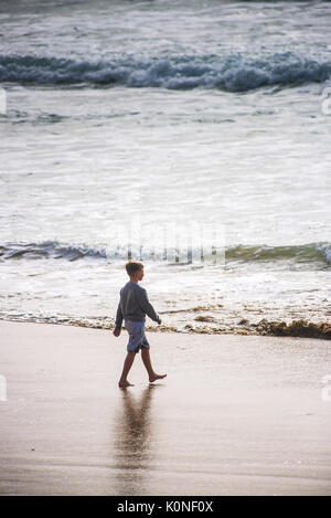 A young boy walking confidently towards the sea. Stock Photo