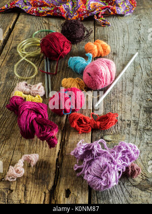 Knitting needles, a crochet hook and a variety of knitting threads on old wooden weathered table Stock Photo