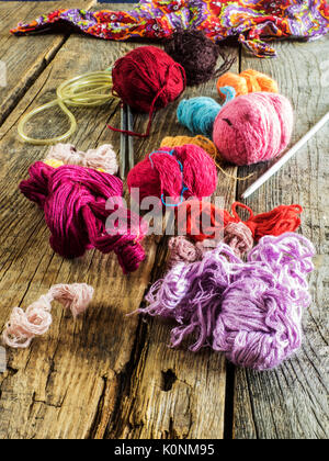 Knitting needles, a crochet hook and a variety of knitting threads on old wooden weathered table Stock Photo