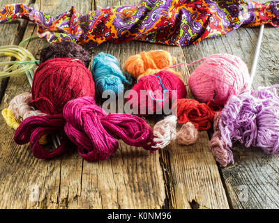 Knitting needles, a crochet hook and a variety of knitting threads on old wooden weathered table Stock Photo