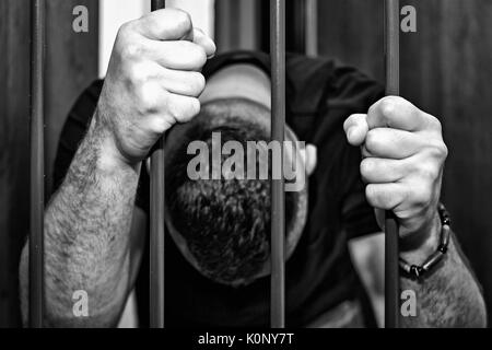 Abstract. Hands of the prisoner on a steel lattice close up. Prison, man in handcuffs. Assassin, a murderer behind the bars. Stock Photo
