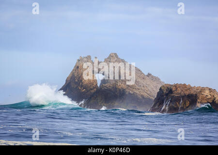 Waves crash on Farallon Islands sea stack with keyhole off coast of San Francisco in the Gulf of Farallon on a sunny, clear day