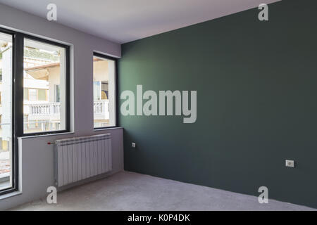 Unfinished interior of apartment  under construction with gray concrete floor, windows and color wall Stock Photo