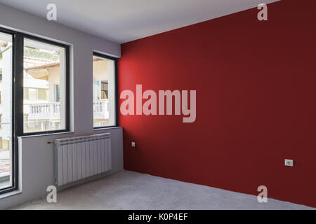 Unfinished interior of apartment  under construction with gray concrete floor, windows and color wall Stock Photo