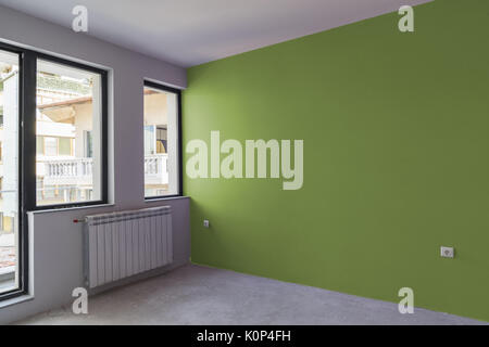 Unfinished interior of apartment  under construction with gray concrete floor, windows and color wall Stock Photo