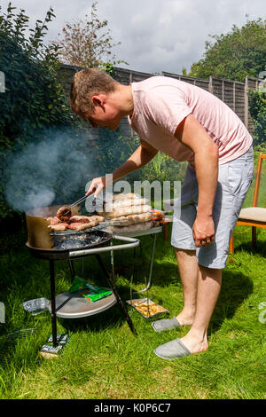 A Young Man Cooking Food On A Barbecue, Sussex, UK Stock Photo