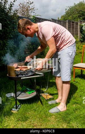 A Young Man Cooking Food On A Barbecue, Sussex, UK Stock Photo