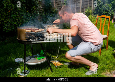 A Young Man Cooking Food On A Barbecue, Sussex, UK Stock Photo