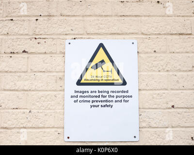 a white placard sign on wall surveillance cctv warning; England; UK Stock Photo