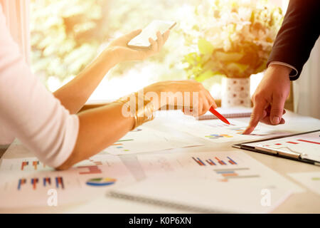 Team members discussing data at meeting. Graphs and charts on table. Business situation Stock Photo