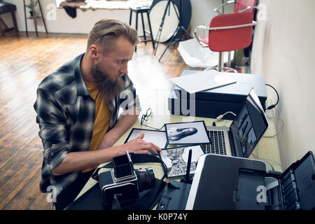 Photographer using laptop while editing photograph on laptop at table in studio Stock Photo