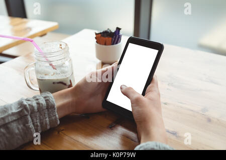 Cropped image of woman using smartphone at table in cafe Stock Photo