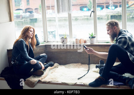 Photographer measuring light while sitting on alcove window seat in studio Stock Photo