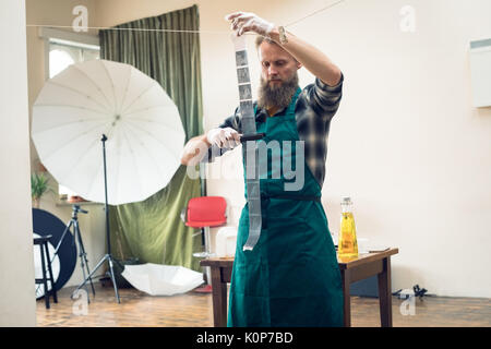 Photographer drying film with equipment while working in studio Stock Photo