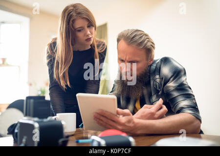 Colleagues lookng over digital tablet at desk in studio Stock Photo