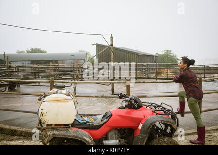 Thoughtful woman leaning on railing near barn Stock Photo