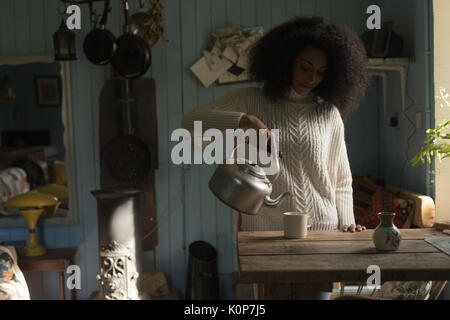 Woman pouring coffee in mug at home Stock Photo