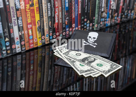 Stacked DVD movies & black pirate wallet with US one dollar bills - for copyright & IP infringement - US-China trade relations, US-China trade war. Stock Photo