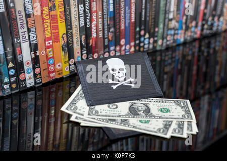 Stacked DVD movies & black pirate wallet with US one dollar bills -  for copyright & IP infringement - US-China trade relations, US-China trade war. Stock Photo