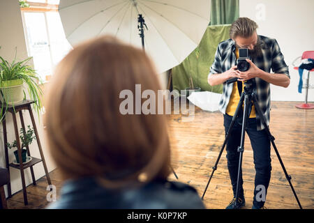 Photographer photographing female fashion model while photographing in studio Stock Photo
