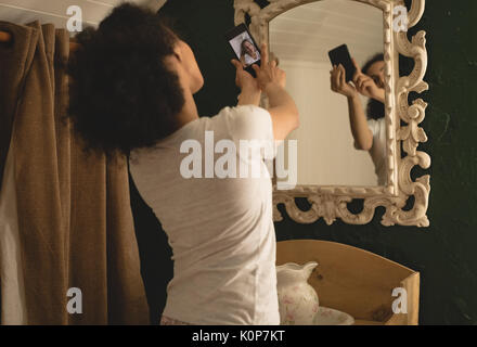 Woman taking a photo on the mobile phone from window at home Stock Photo
