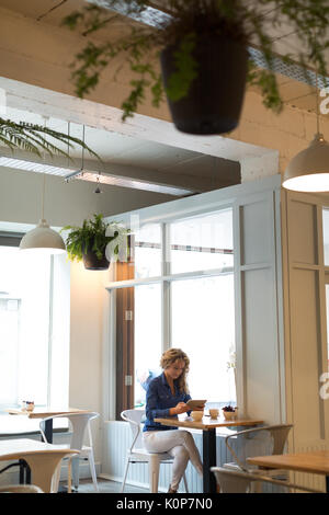 Woman using digital tablet while sitting at table in cafe Stock Photo
