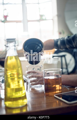 Cropped image of man pouring liquid in beaker while working in studio Stock Photo