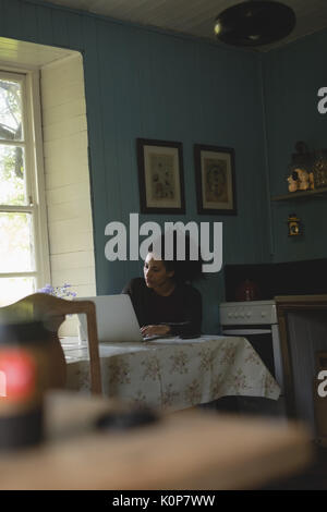 Woman using laptop while sitting on table at home Stock Photo