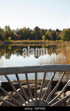 Overlooking a rustic railing that is on the edge of a man-made pond at the Wild Center at Tupper Lake in the Adirondacks of New York state. Stock Photo