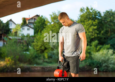 Masculine man with dumbbell by the river Stock Photo
