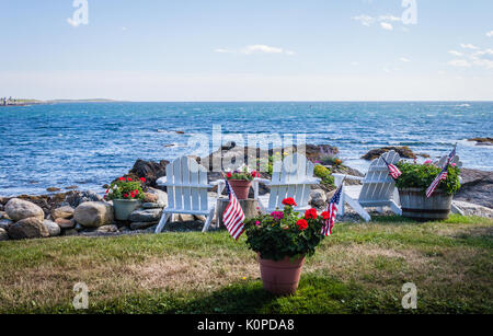 Adirondack chairs facing the clear blue bay on a clear summer day Stock Photo