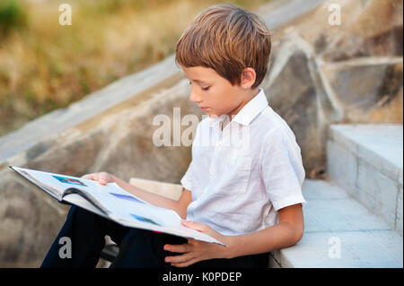Child doing his homework outdoors after school. Stock Photo
