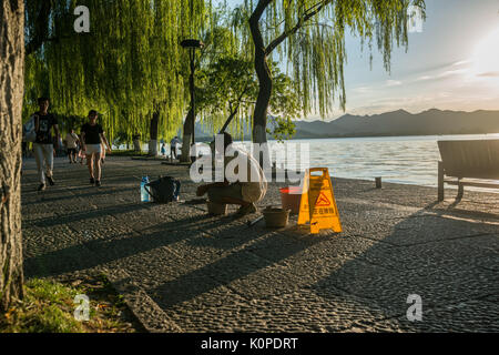 Chinese manual worker repairing the stone path, sidewalk in early evening Stock Photo