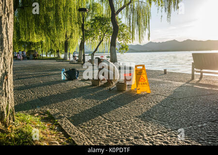 Chinese manual worker repairing the stone path, sidewalk in early evening Stock Photo