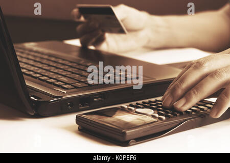 Young man calculating and holding credit card with laptop  about cost for shopping online. Stock Photo