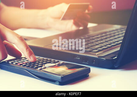 Female calculating and holding credit card with laptop  about cost for shopping online. Stock Photo
