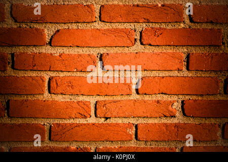 Red brick wall segment with yellow/reddish junctions background. Bricks with pronounced rough texture. Stock Photo