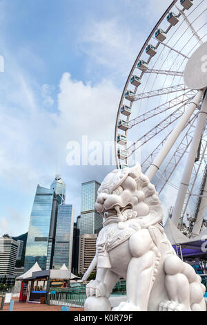 A traditional Chinese guardian lion statue with Hong Kong's skyline at Central Pier, Victoria Harbor, on Hong Kong Island. Common and popular in Chine Stock Photo