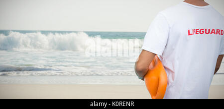 Mid section of male lifeguard with rescue buoy against two starfish kept on sand Stock Photo