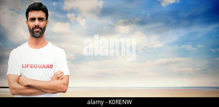 Portrait of male lifeguard with arms crossed against serene beach landscape Stock Photo